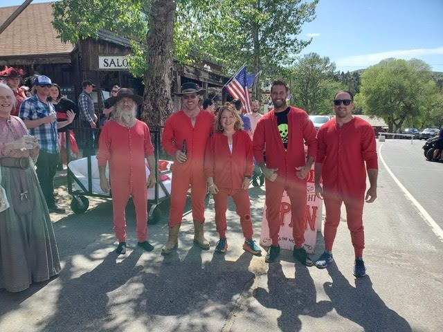 A group of people in red jumpsuits are standing in front of a saloon