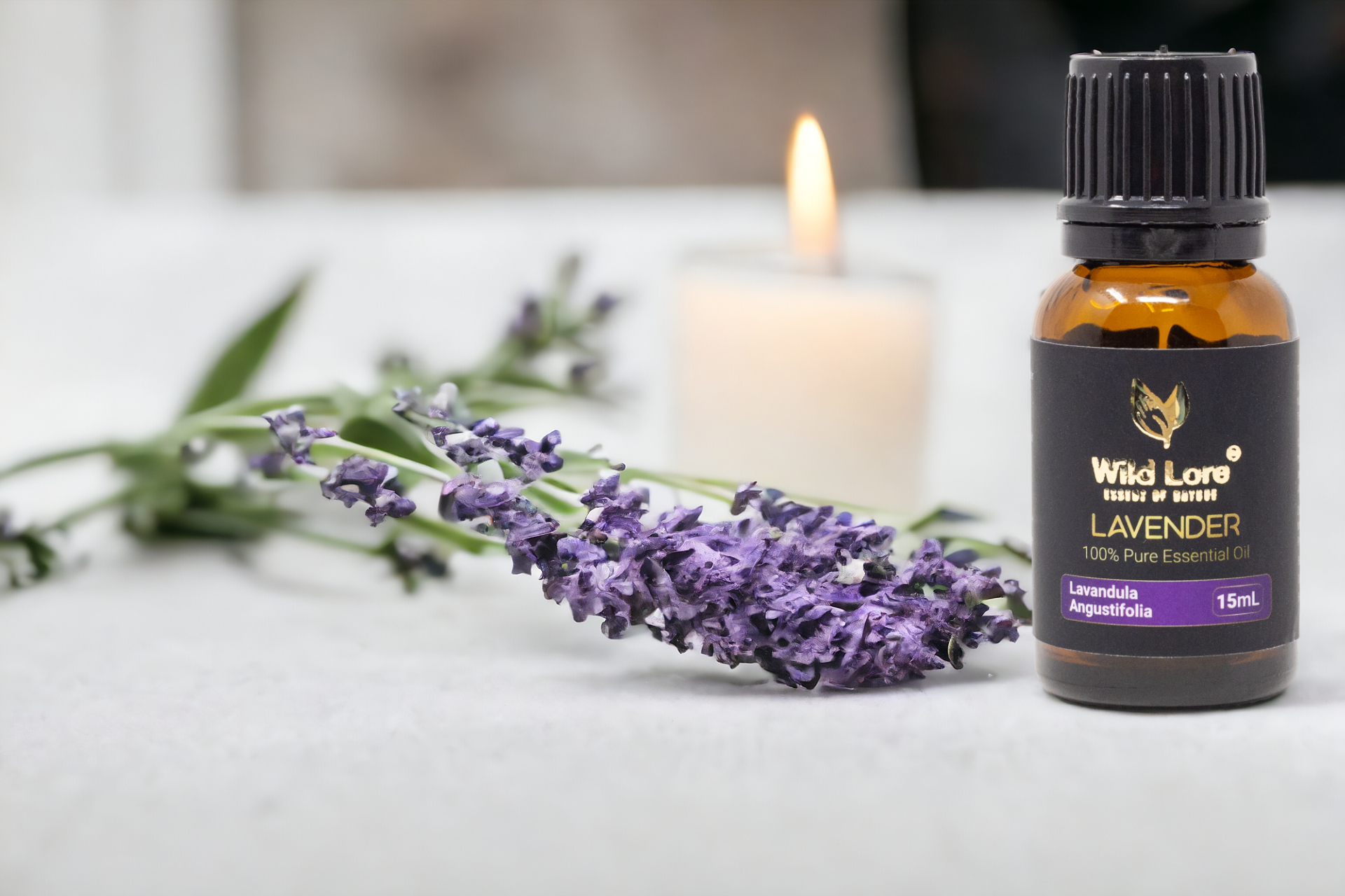 A bottle of lavender essential oil next to a bunch of lavender flowers and a candle.