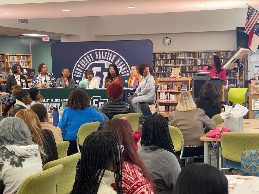 A group of people are sitting at tables in a library.