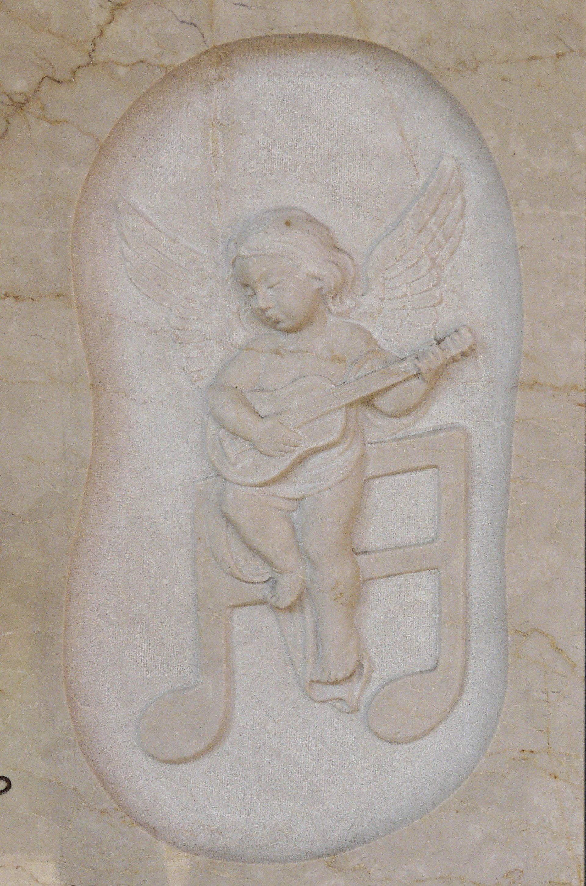 bassorilievo su marmo beige rappresentante un bimbo che suona