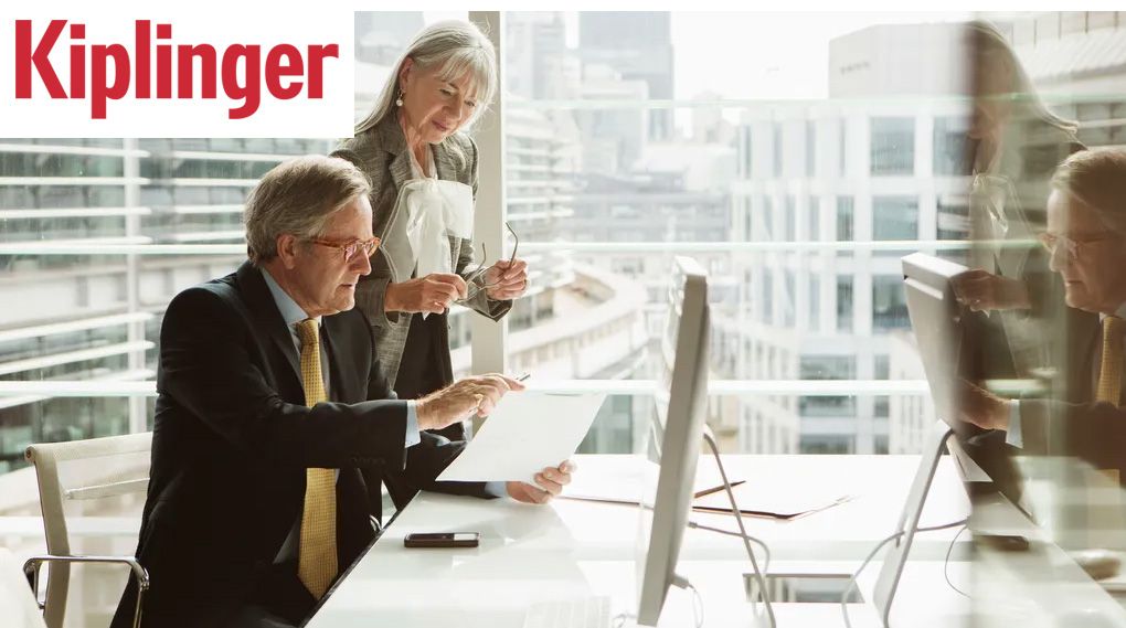 People looking at documents in an office with large windows. The Kiplinger logo is in the top left corner.