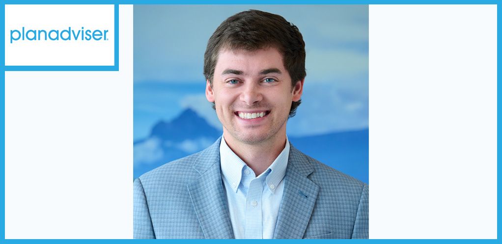 Smiling man in a suit jacket, mountains in the background, 