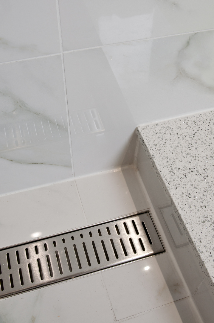 A close up of a drain in a bathroom next to a counter.