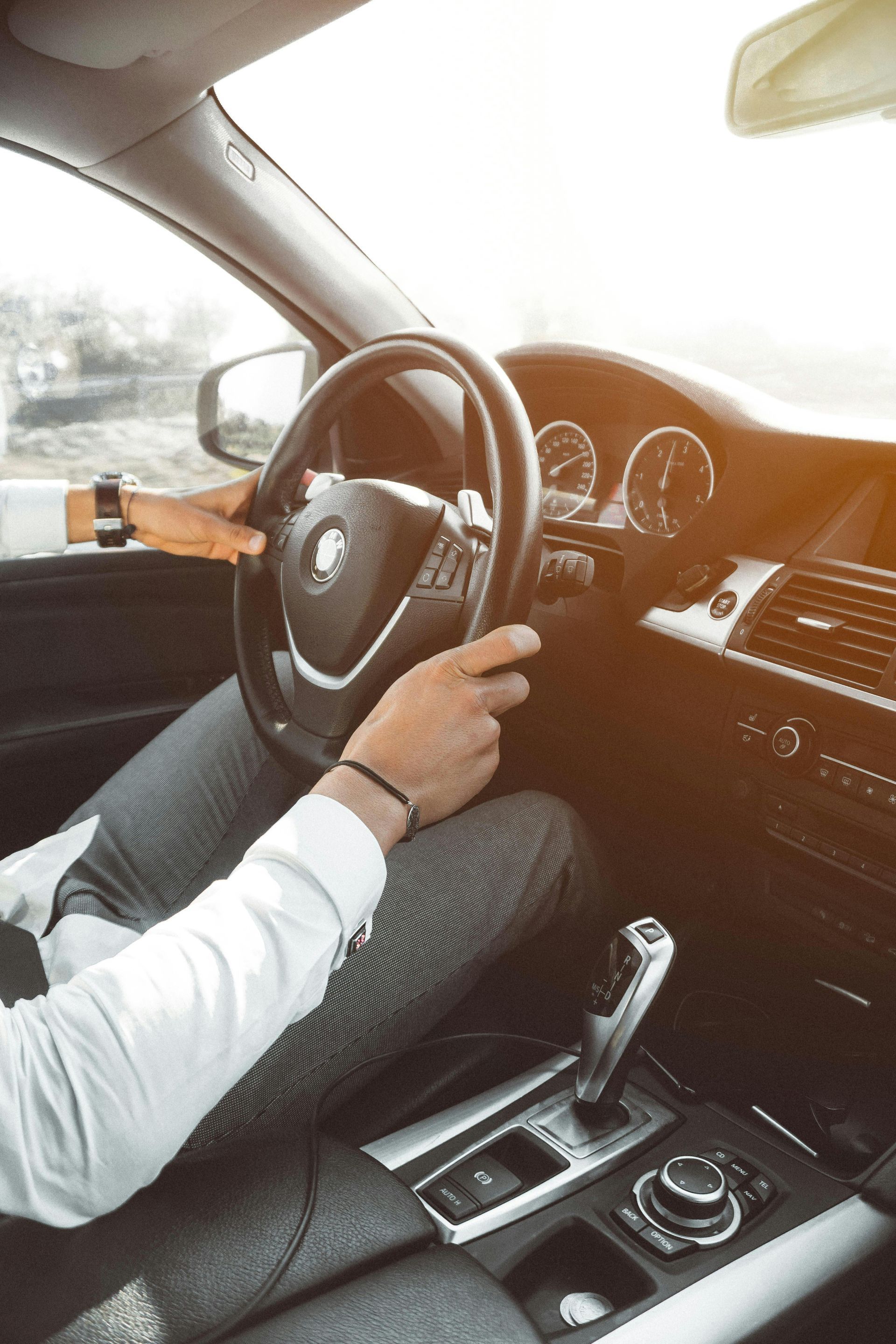 A man is driving a car with his hands on the steering wheel