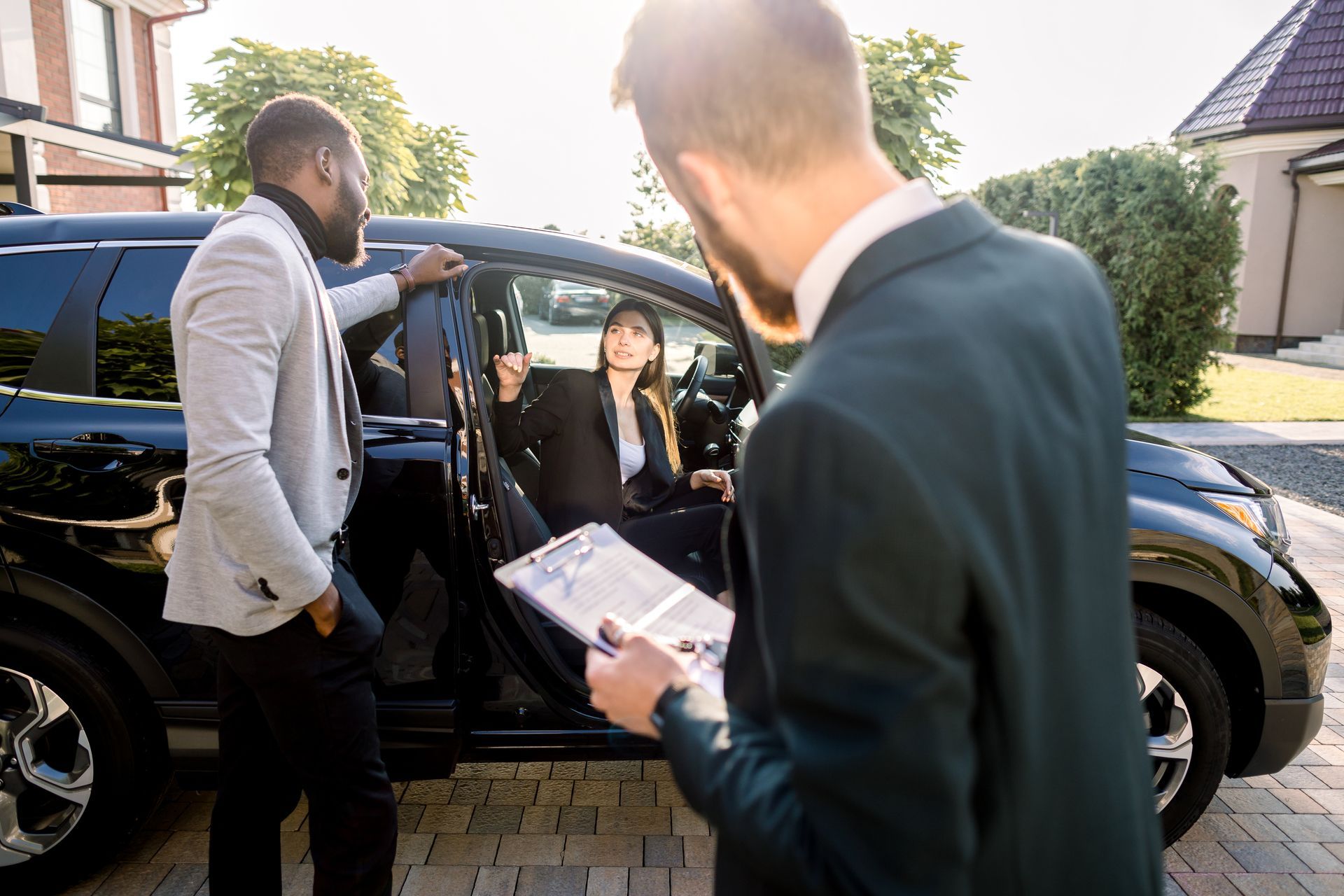 A man in a suit is standing next to a woman in a car.