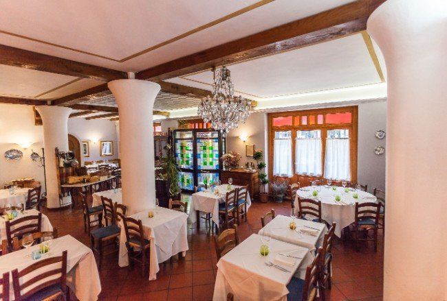 Sala di un ristorante con tavoli e sedie di legno