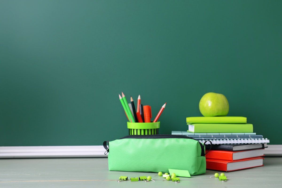 Photo of books and an apple in front of a chalkboard