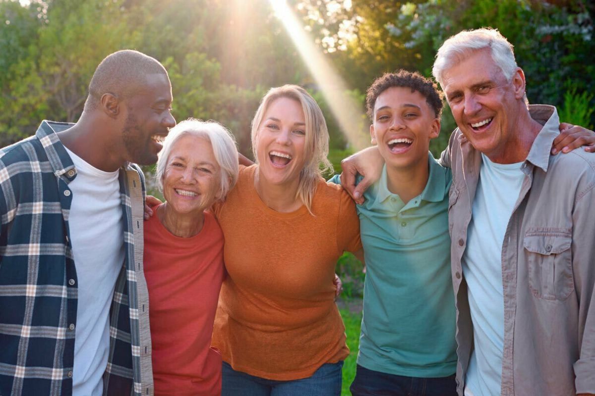 A group of smiling people are posing for a picture together in a park.