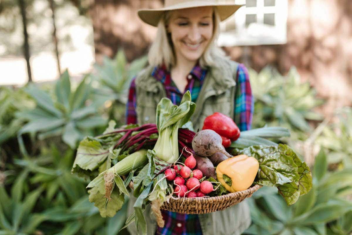 A woman is holding a basket of fresh spring produce.