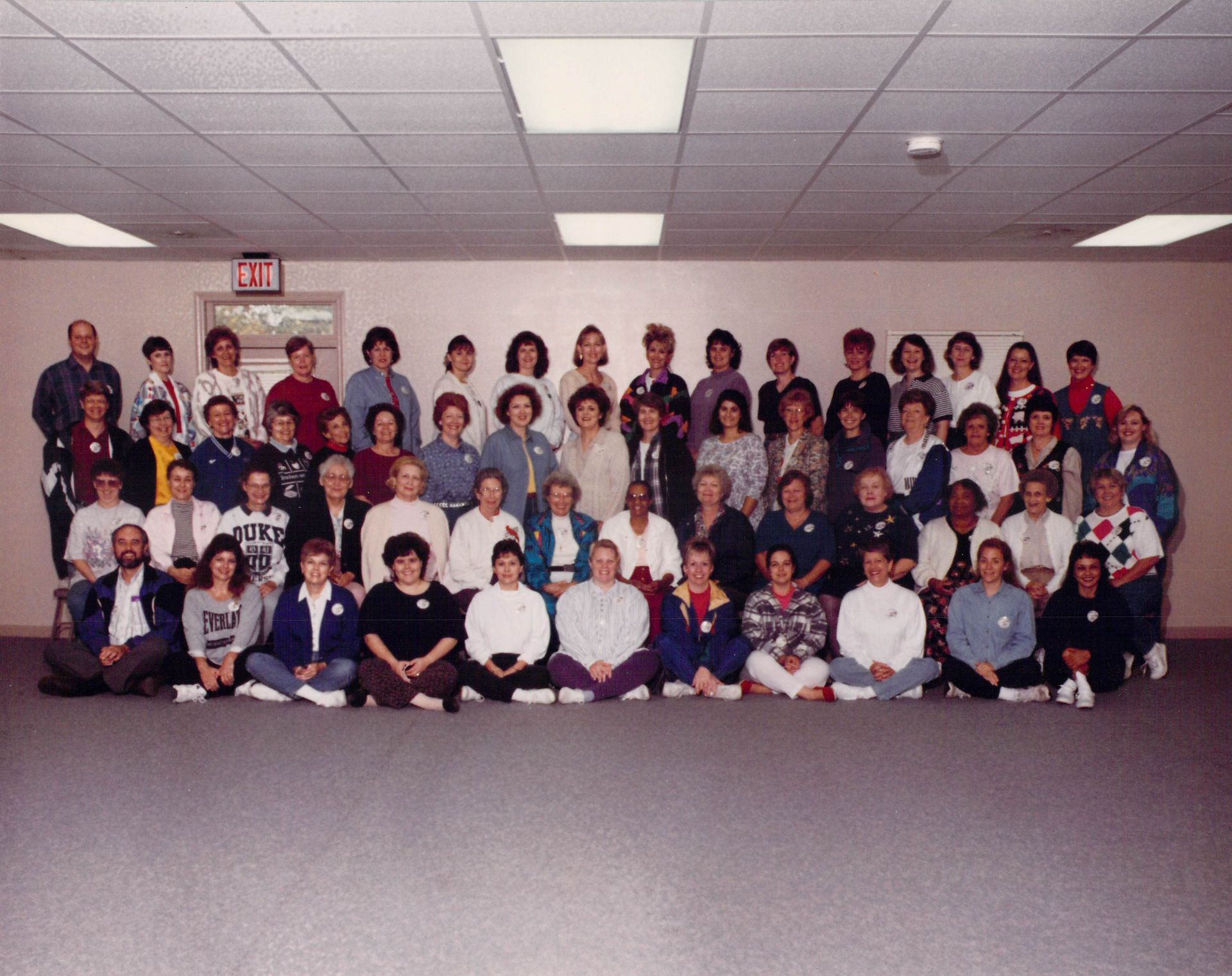 A large group of people are posing for a photo in front of an exit sign
