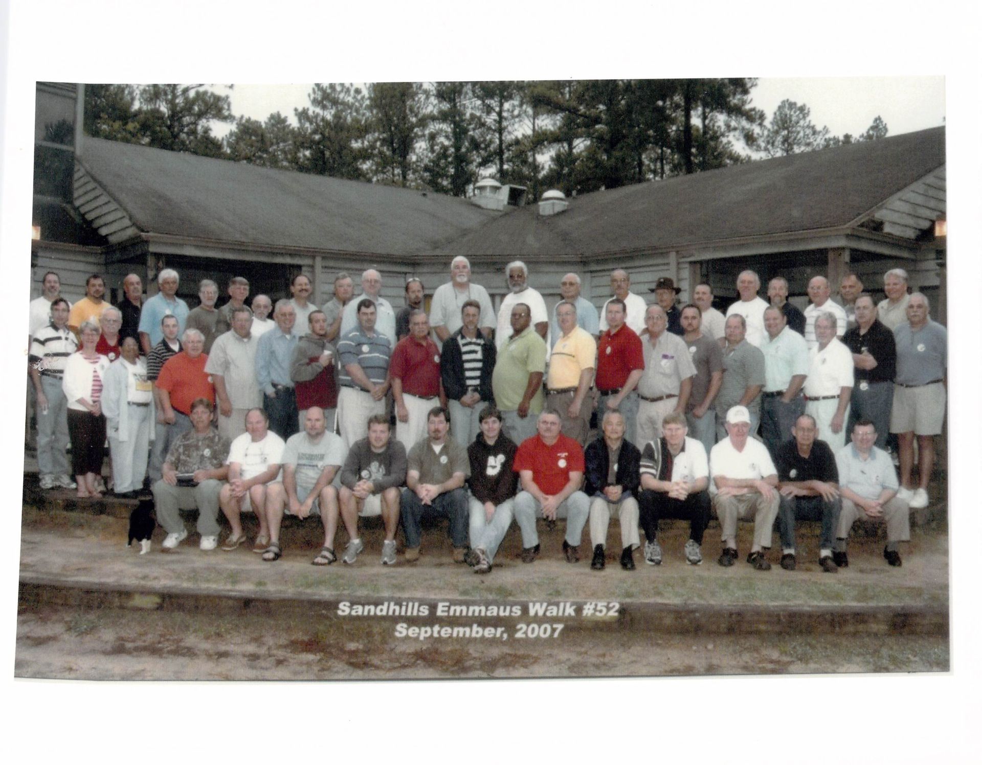A large group of men are posing for a photo in front of a building with the date september 2007