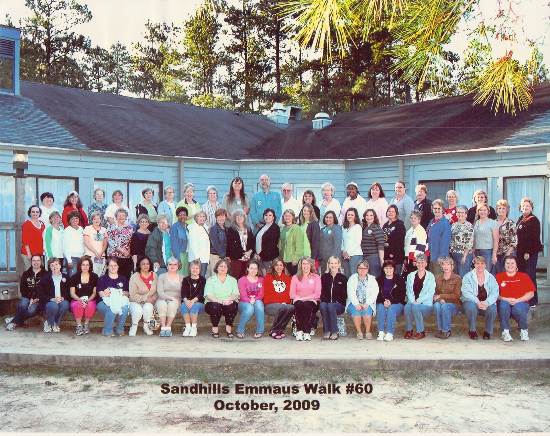 A large group of people are posing for a photo in front of a building that says sandhills emmaus walk # 60 october 2009