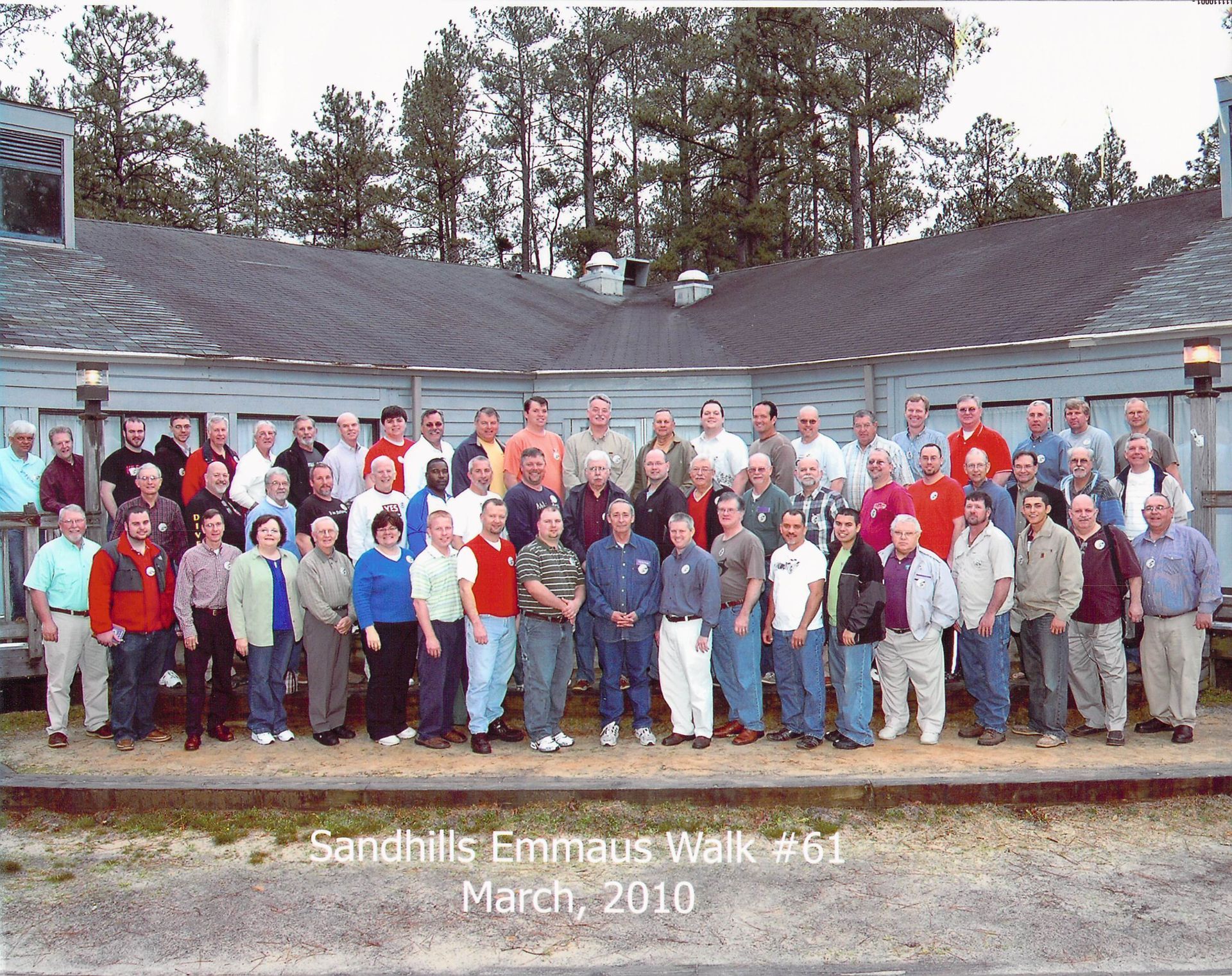 A group of people posing for a photo in front of a building that says sandhills finnhaus walk # 61 march 2010