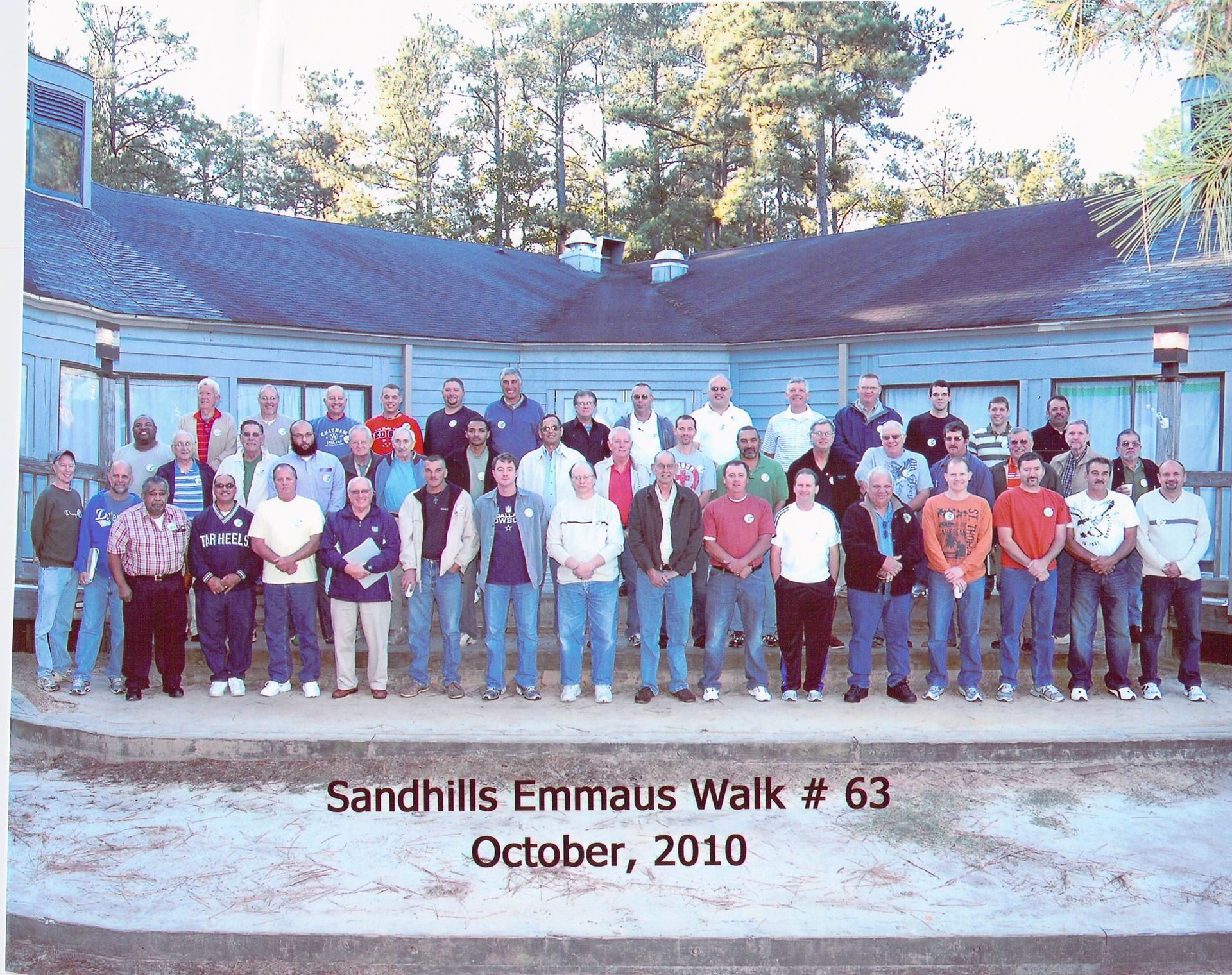 A group of people standing in front of a building that says sandhills emmaus walk # 63 october 2010