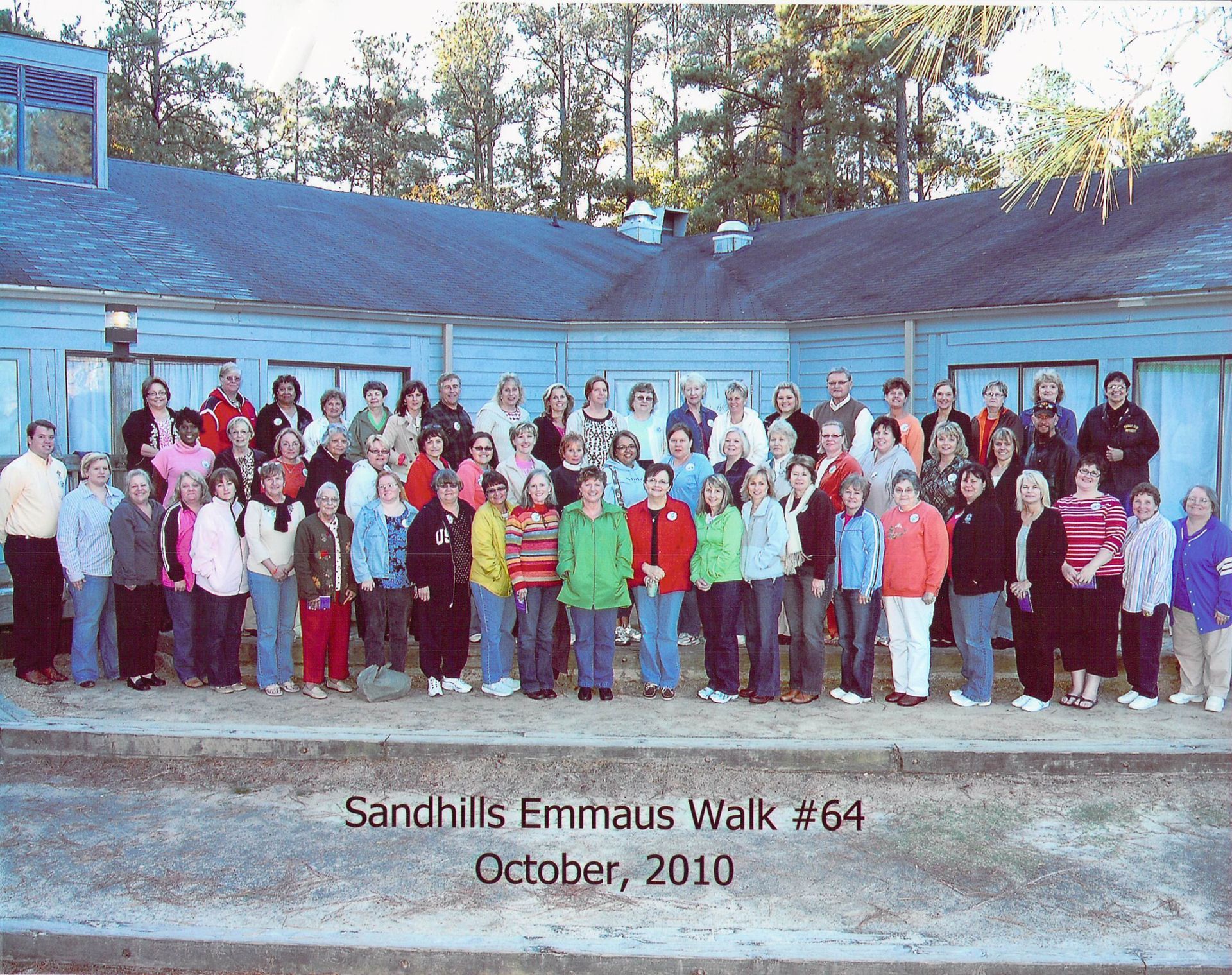 A group of people standing in front of a building that says sandhills emmanuel walk # 64 october 2010