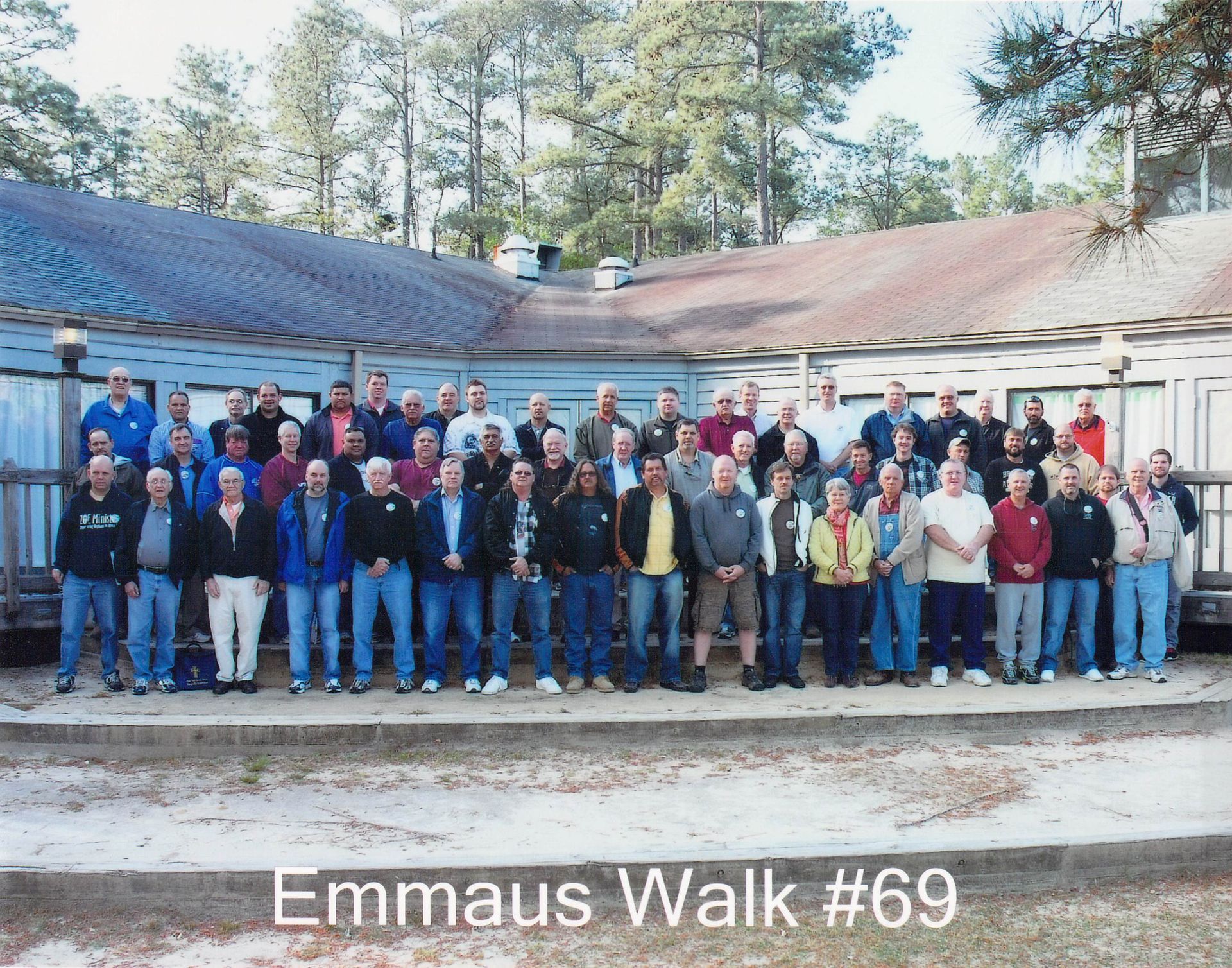 A group of people standing in front of a building with the caption emmaus walk # 69