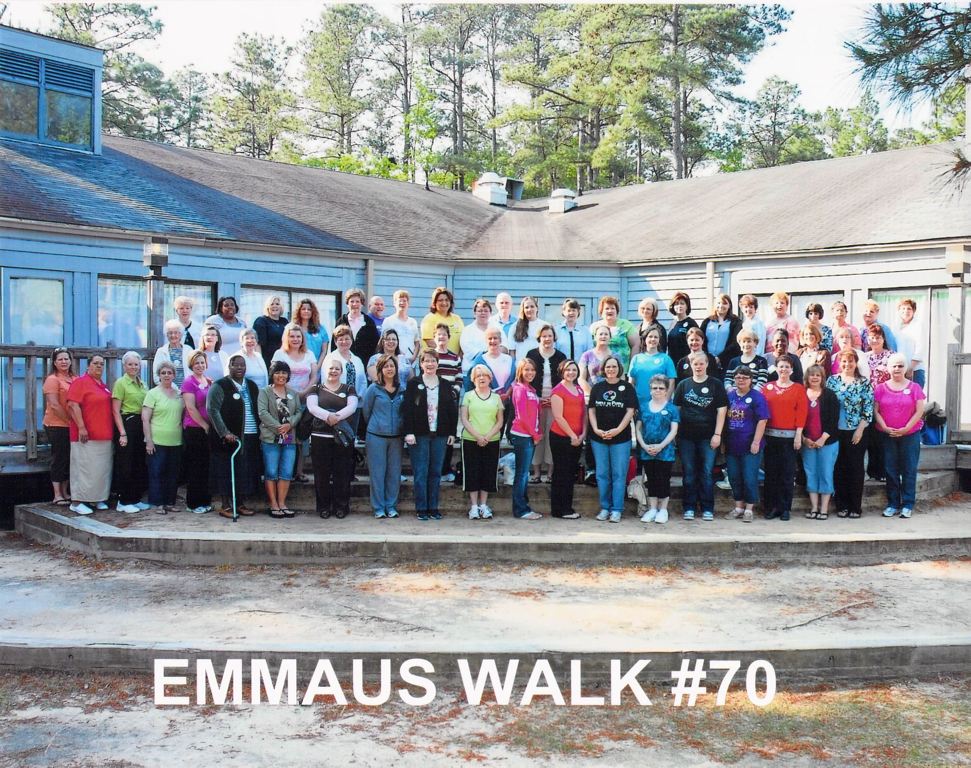 A large group of people standing in front of a building with the words emmaus walk # 70 on the bottom