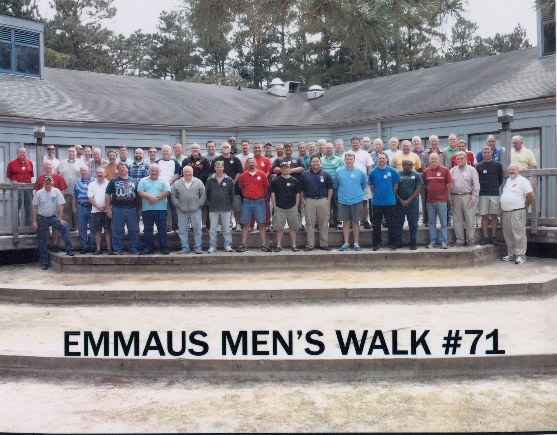 A large group of men standing in front of a sign that says emmaus men 's walk # 71