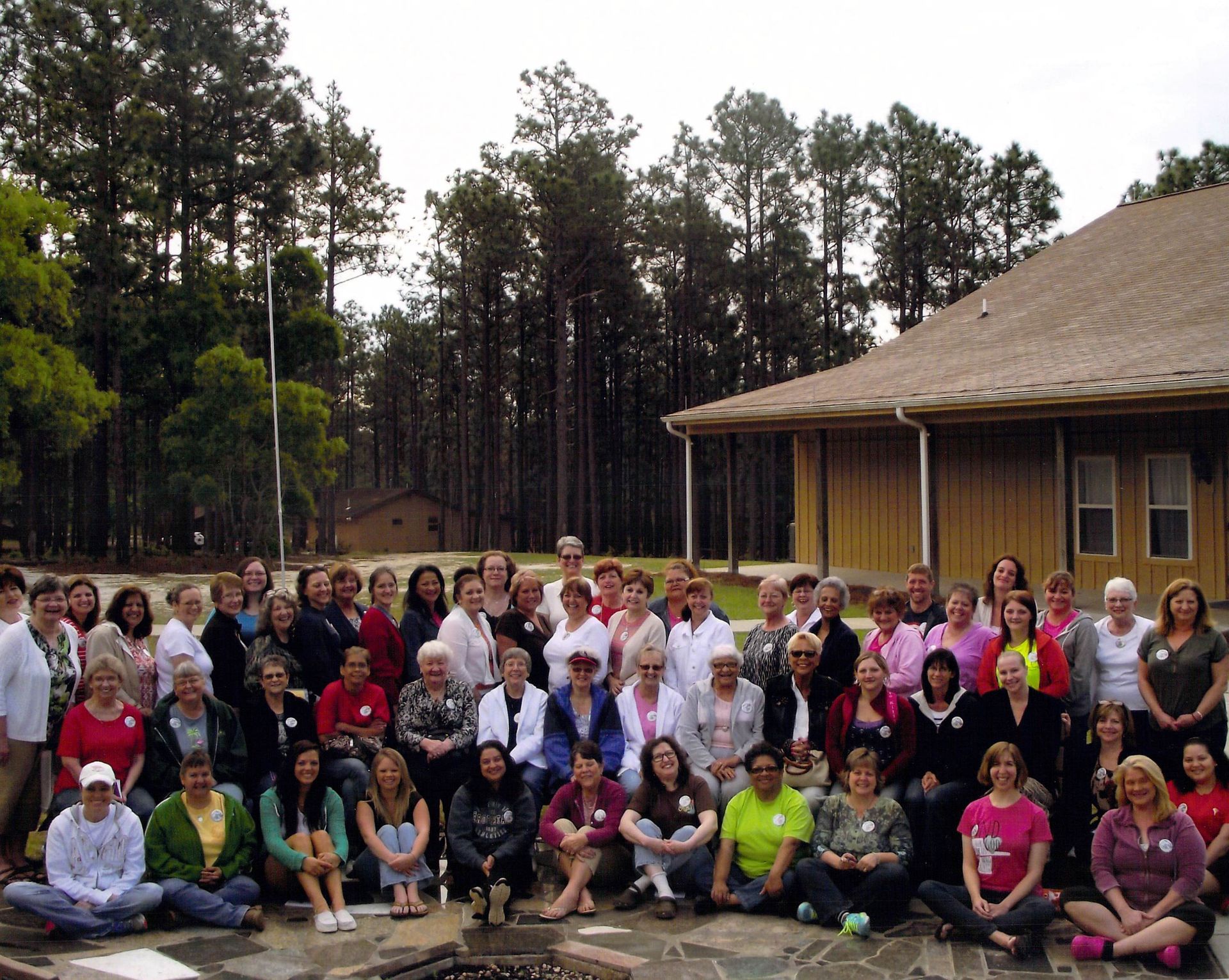 A large group of people are posing for a picture in front of a house