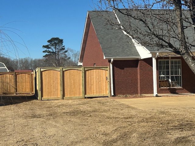 Wooden fence next to a red brick house; sunny day.