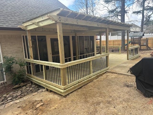 Newly constructed wooden screened porch with railing and pergola in backyard setting.