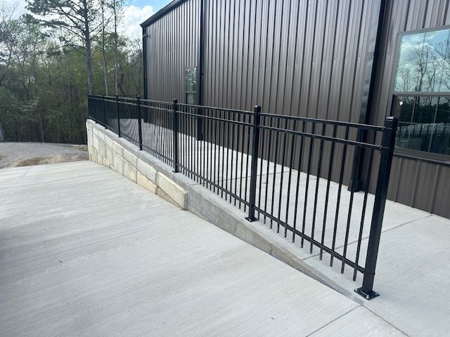 Black metal railing on a concrete ramp next to a brown industrial building.