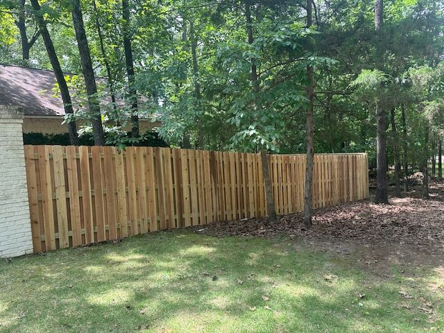 Wooden fence in backyard, bordering trees and greenery.