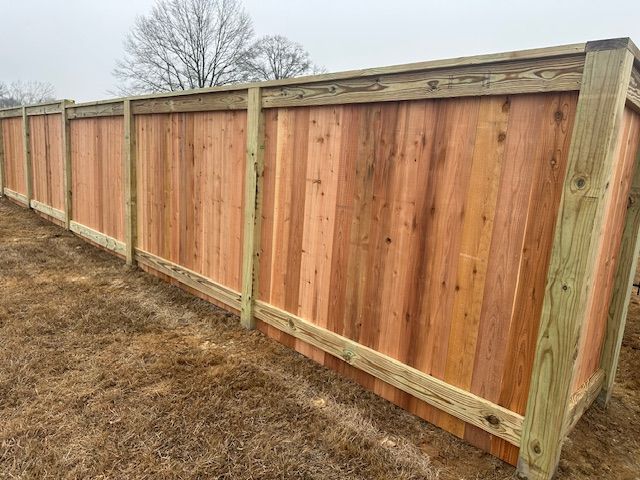 Wooden privacy fence in an open grassy area.