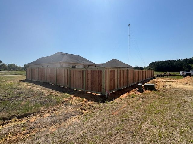 Wooden fence surrounding a house under a clear blue sky.
