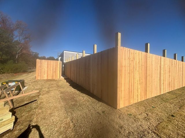Wooden fence being built outdoors on a sunny day.