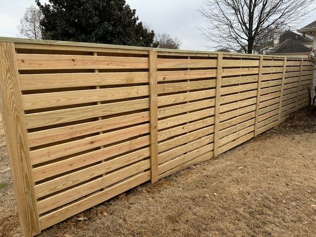 Wooden horizontal slat fence in a yard.
