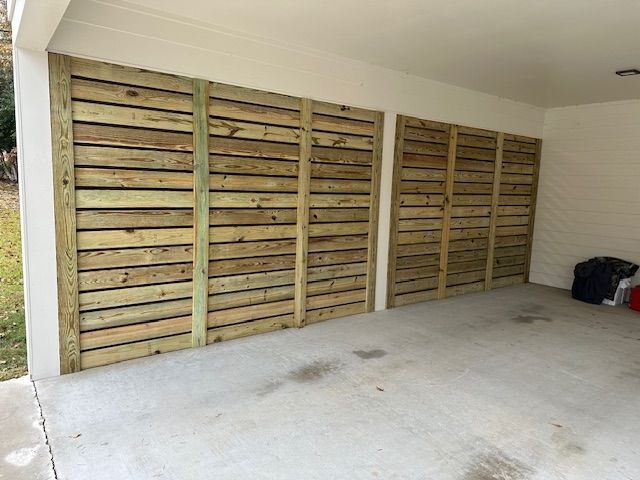 Exterior of a garage with wooden slat panels covering the walls. Concrete floor, white walls.