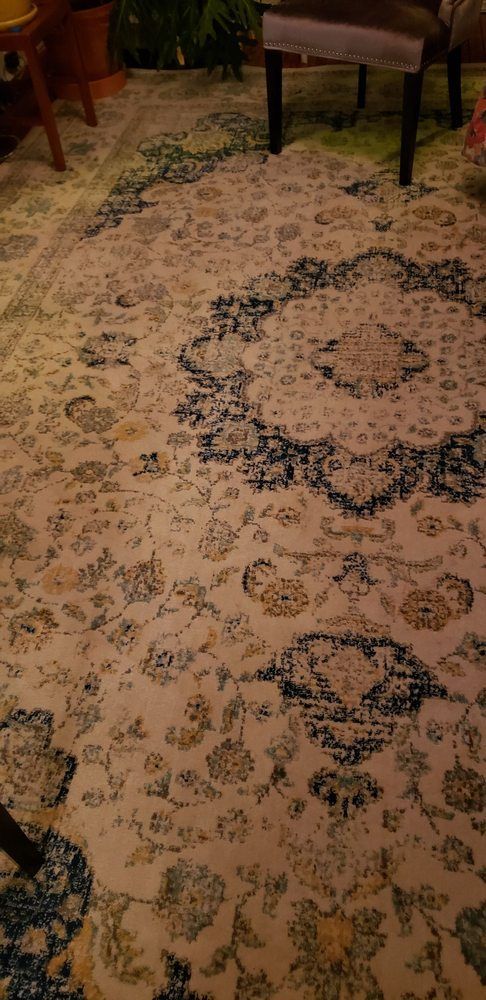A patterned rug with a cream background and dark blue and tan floral designs.