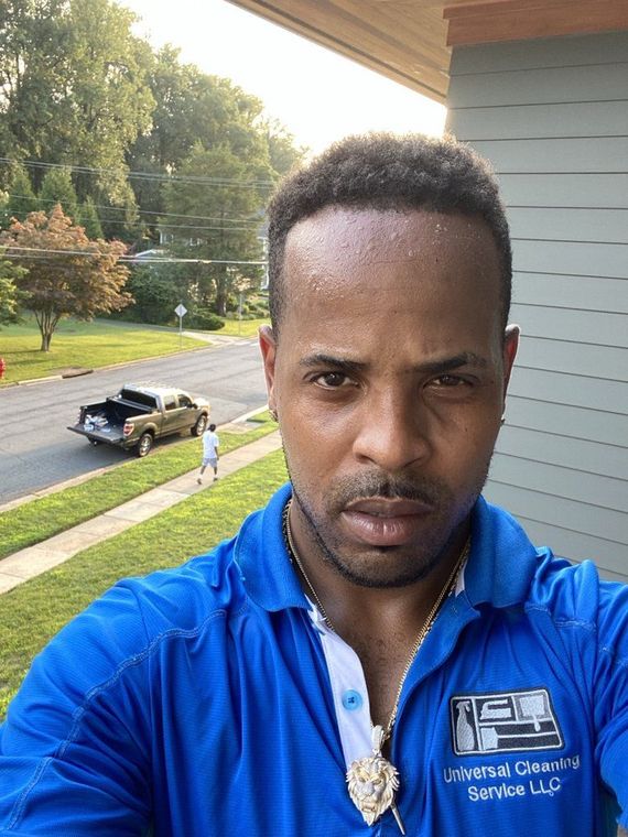 A man with short dark hair and a blue polo shirt looks at the camera outside.