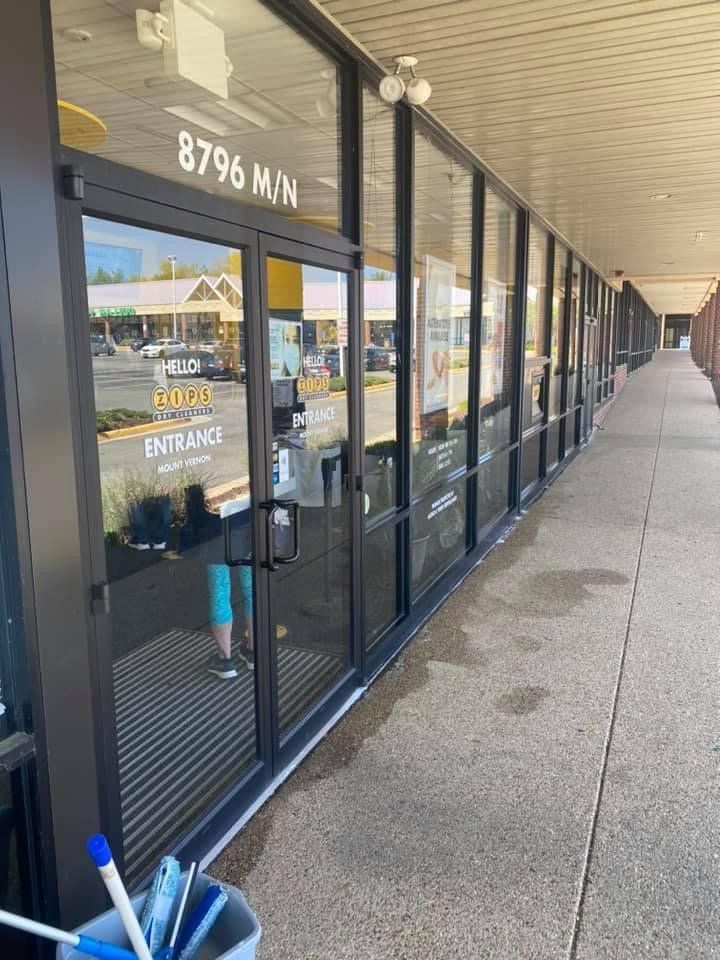 Exterior view of a storefront with a glass door and windows. The door has 