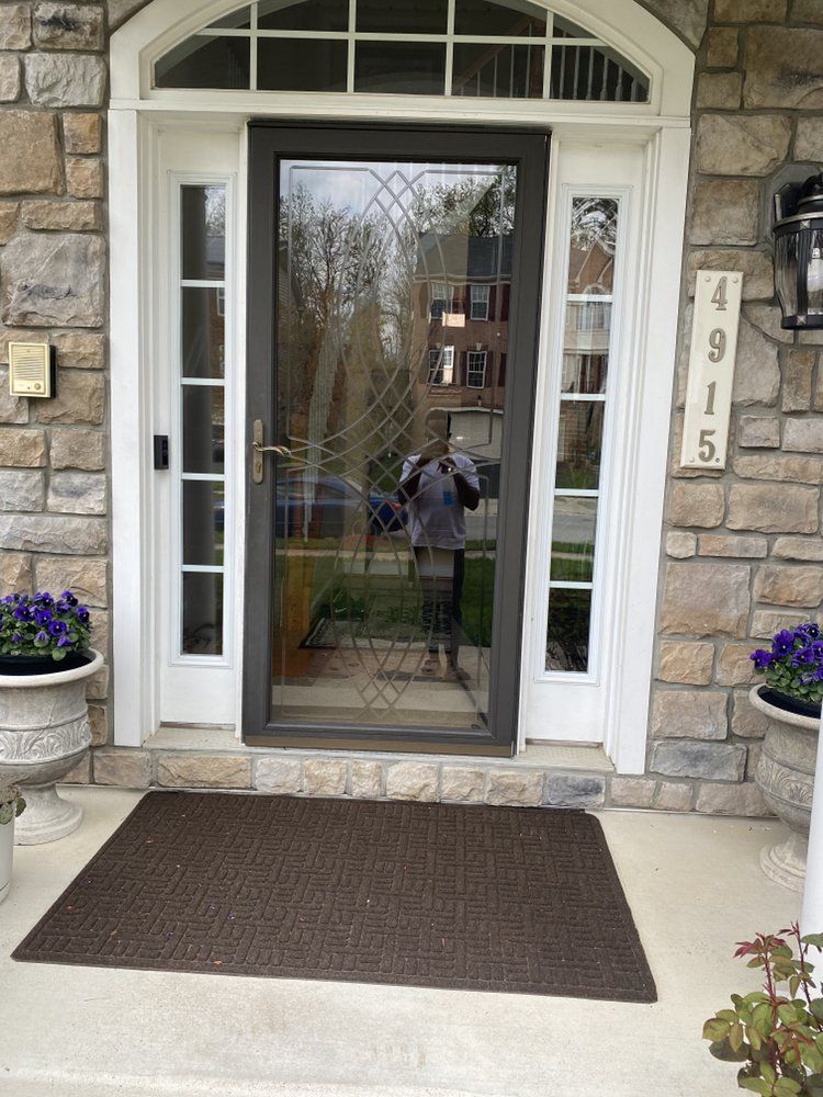 Front door of a house with stone facade. A person is visible in the glass storm door reflection. The address is 4915.