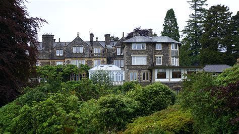 Een groot huis is omgeven door bomen en struiken.