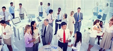 Een grote groep mensen staat in een kamer en praat met elkaar.