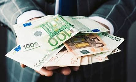 Een man in pak en stropdas houdt een stapel geld in zijn handen.