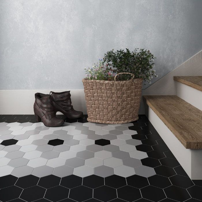 Hal met tegelvloer met patroon, mand met bloemen en laarzen bij de trap.