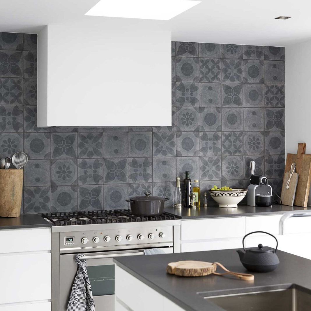 Moderne keuken met grijze achterwand, witte kasten en roestvrijstalen fornuis.