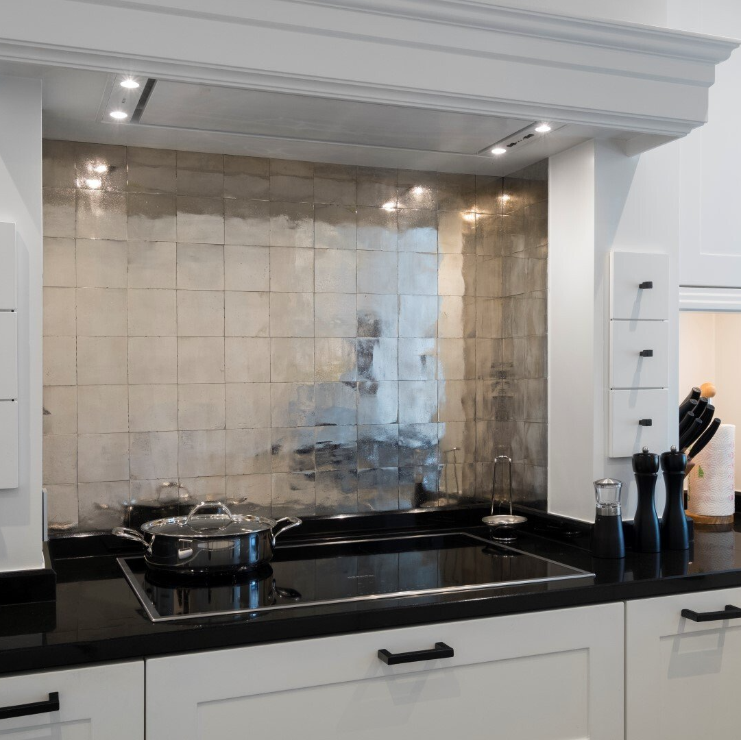 Moderne keuken met zwarte aanrechtbladen, een spiegelachterwand en witte kasten.