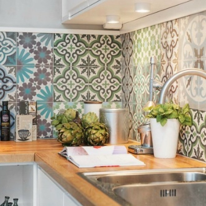 Keukenhoek met gebloemde tegels, houten aanrecht, roestvrijstalen spoelbak en artisjokken.