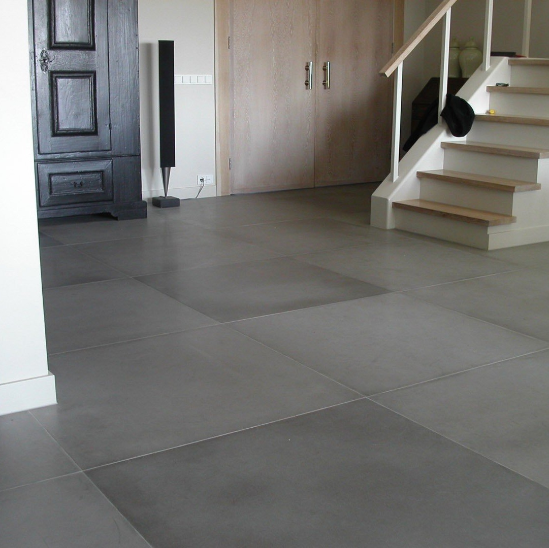 Grijze schuimtegels op de vloer in een kamer vlak bij een houten trap en een gesloten zwarte kast.