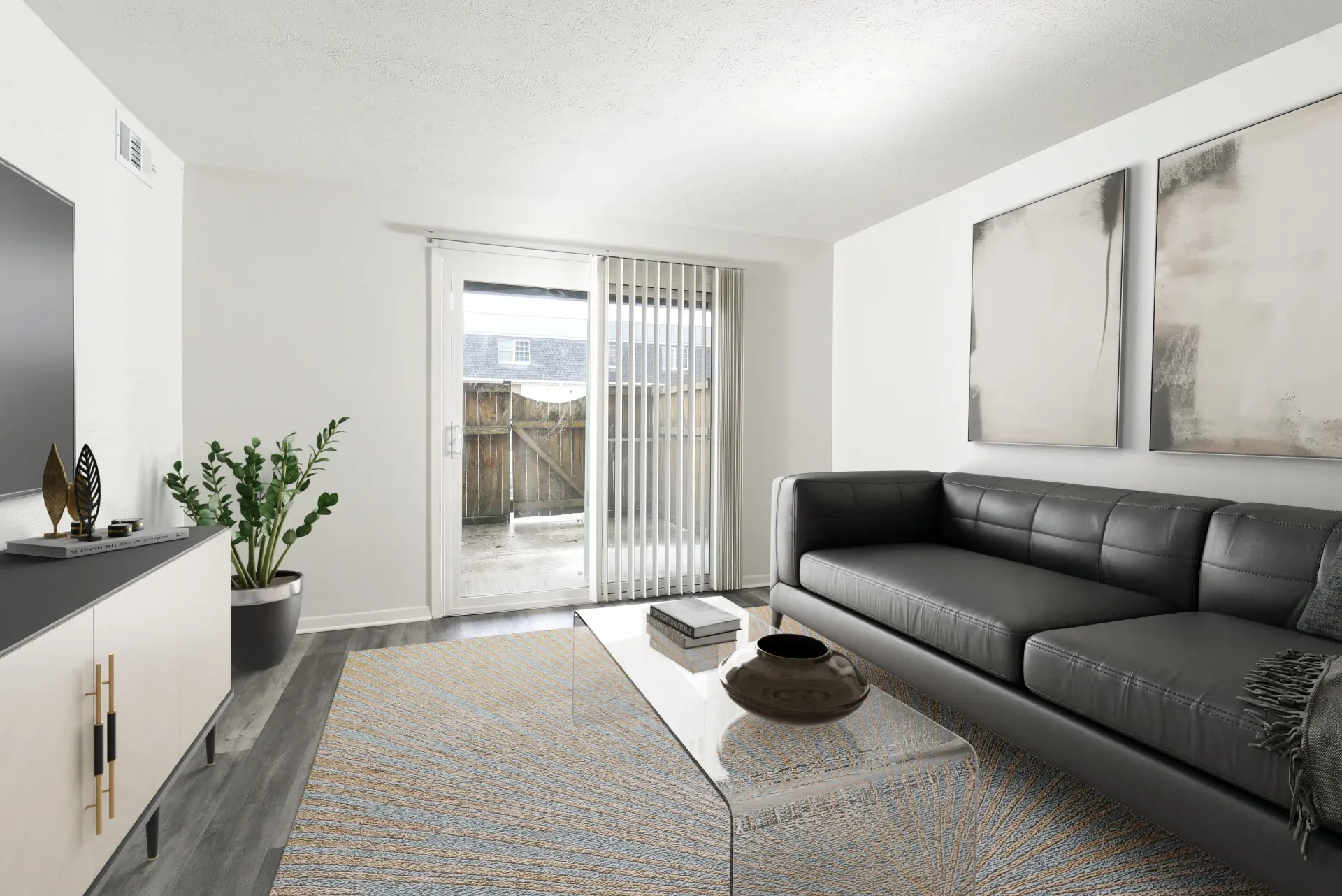Modern living room with a gray sofa, coffee table, and a sliding glass door with vertical blinds to a patio.