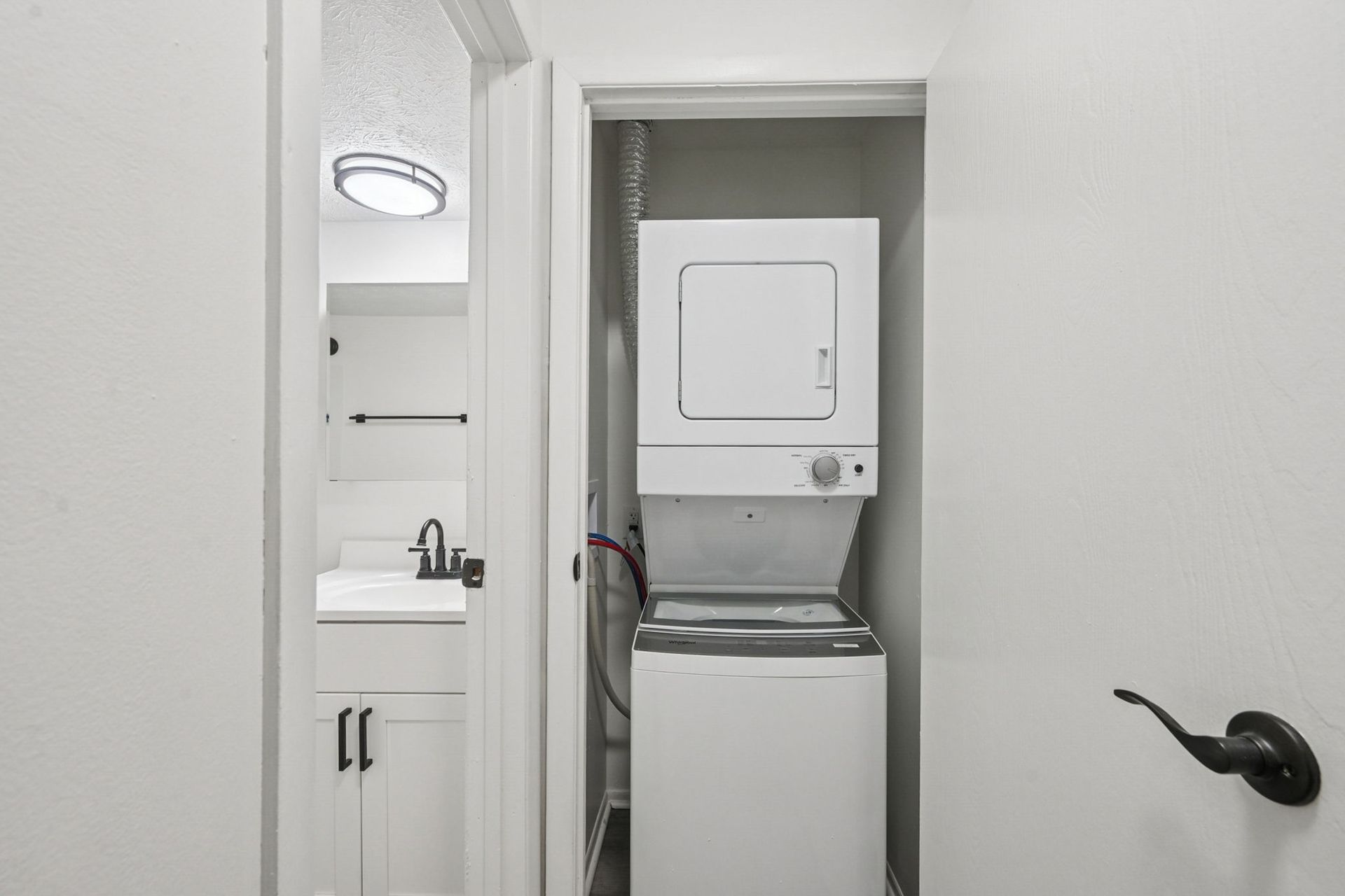 Stacked washer and dryer in a laundry closet beside the bathroom