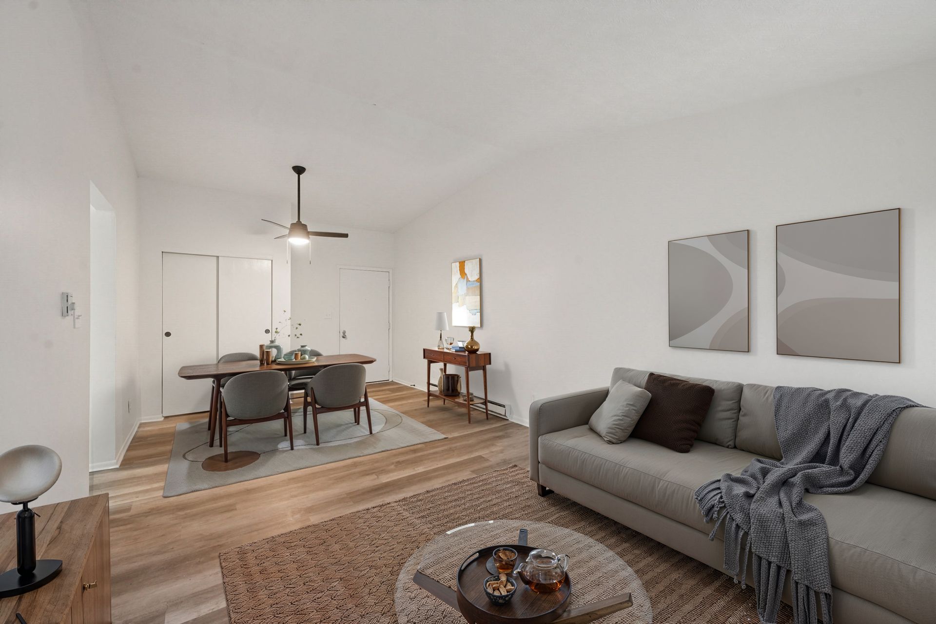 Open living room with gray sofa, dining table, hardwood floors, and abstract wall art.
