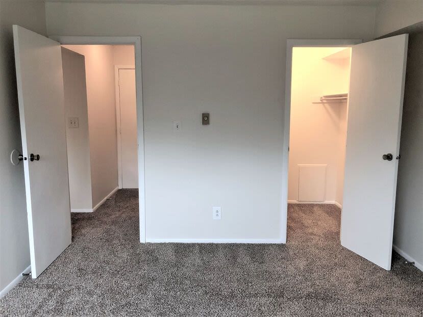 Interior of an empty apartment with two open closet doors on either side.