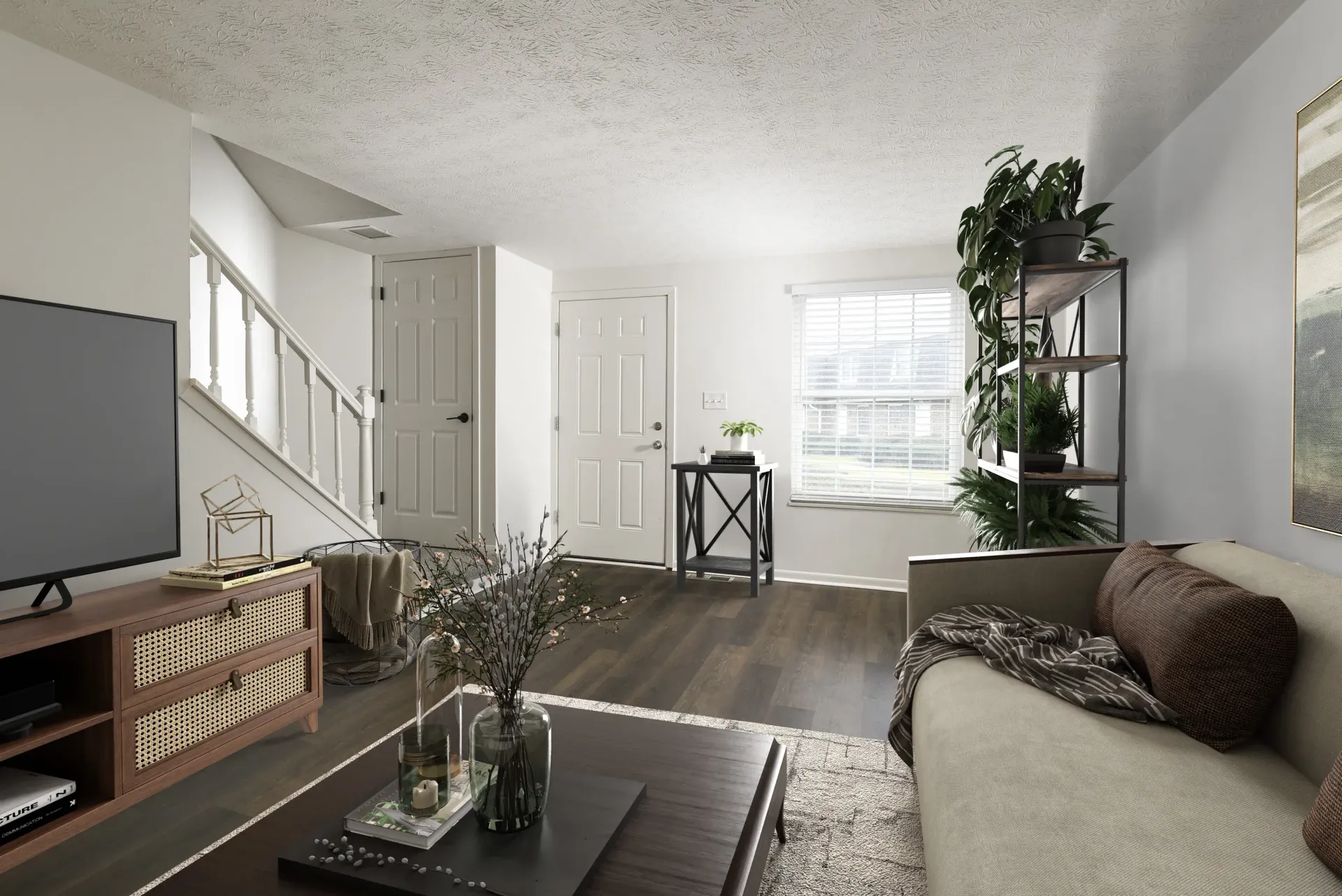 Living room in an apartment with sofa, coffee table, TV stand, stairs, and shelves.