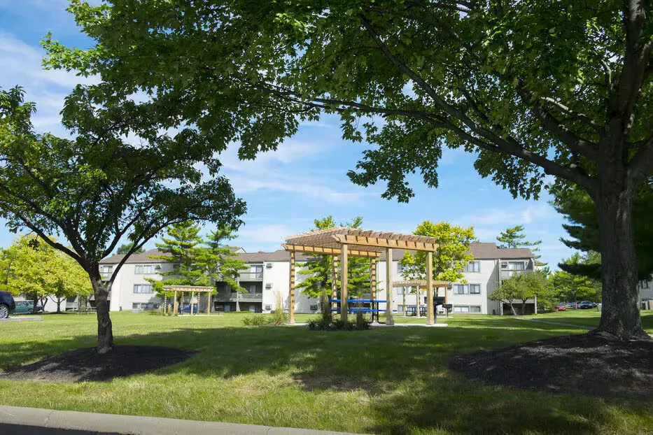 Apartment community courtyard with trees, a pergola, and benches.